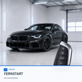 BMW Fahrzeugschlüssel vor dunklem Fahrzeug für Fernstart-Aktivierung